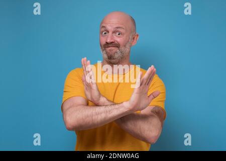 Senior handsome man showing stop sign on blue background. Prohibition symbol Stock Photo
