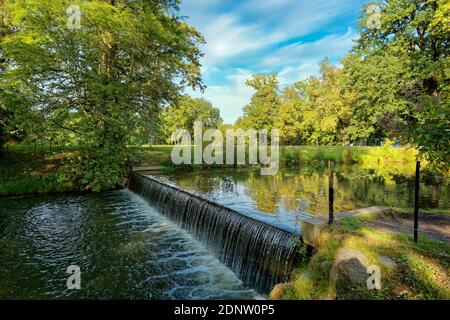River flowing over a small weir in a park in summer, Germany Stock Photo