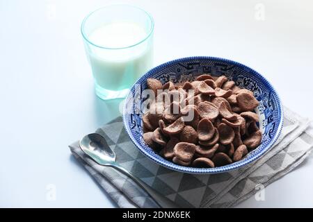 chocolate corn flakes in a bowl and milk on white background  Stock Photo