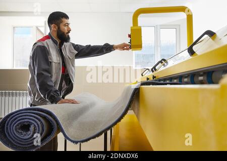 Man operating carpet automatic washing machine in professional laundry service Stock Photo