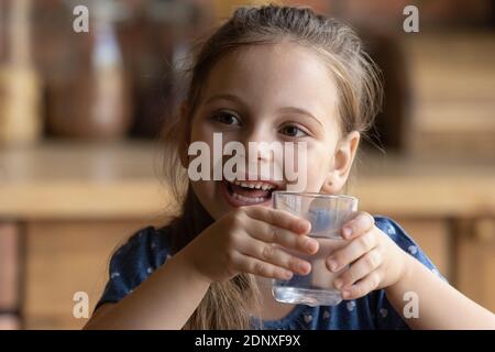 Happy little girl feeling glad drinking cool water from glass Stock Photo