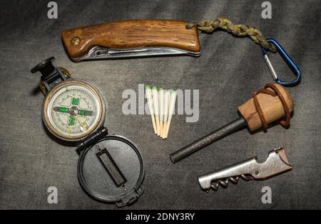 EDC. Wearable survival kit. Folding knife, compass and hunting matches with flint. Tools for overnight in the forest. Tools for the expedition. Stock Photo