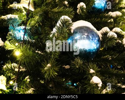 snow and ball on decorated Christmas tree close up outdoors at night Stock Photo