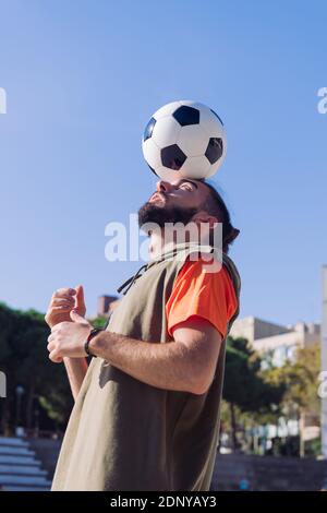 vertical portrait of a soccer player playing balancing the ball on his head , concept of healthy lifestyle and urban sport in the city, copy space for Stock Photo