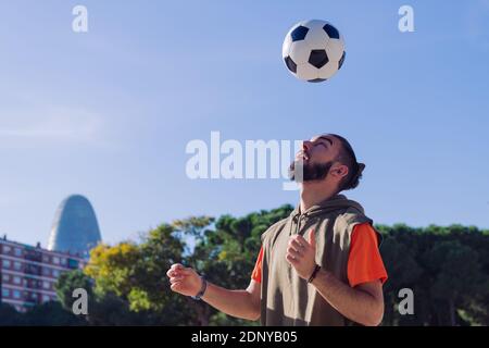 portrait of a football player playing giving head hits to the the ball in the city, concept of healthy lifestyle and urban sport in the city, copy spa Stock Photo