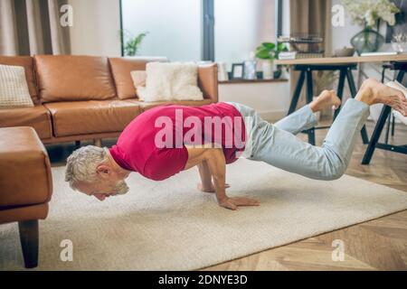 Grey-haired fit man doing yoga and looking strong Stock Photo