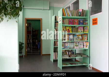 Shelves with children's books are in the village library. Stock Photo