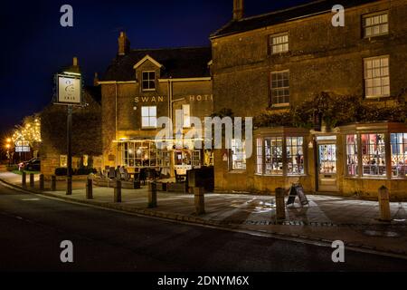 UK, Gloucestershire, Broadway, The Green, Swan Hotel and Cheltenham House antique shop illuminated for village late night Christmas shopping Stock Photo