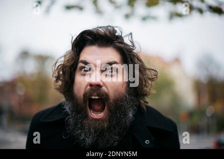 Bearded man making faces outdoors Stock Photo