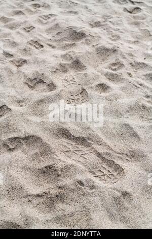 Footprints on sandy beach in sunshine. Leave no trace metaphor, muddled messaging, mixed signals., Stock Photo