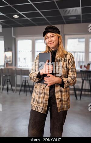 Smiling woman standing in office and looking at camera Stock Photo
