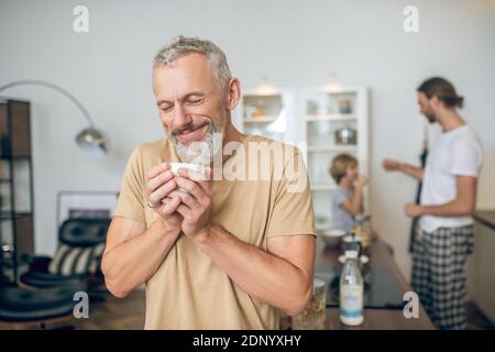 Grey-haired man having morning coffee and feeling good Stock Photo