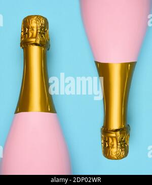 Two Pink Champagne bottles on a blue teal background. Horizontal high angle shot. Stock Photo