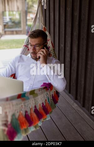 Man on hammock talking via cell phone Stock Photo