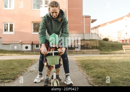 Mother helping daughter to cycle Stock Photo