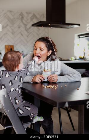 Mother carry toddler son sitting at table Stock Photo