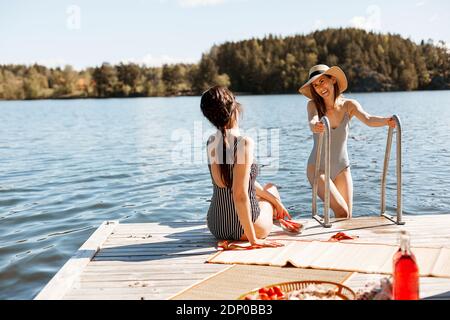 Female friends relaxing on jetty Stock Photo
