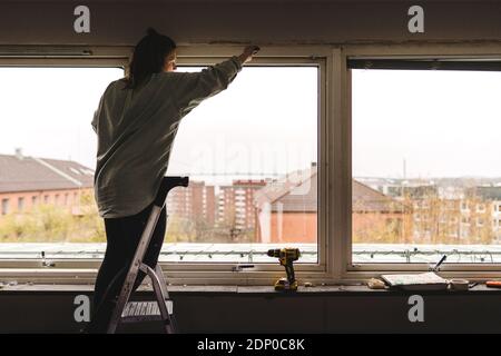 Woman sanding window frame Stock Photo