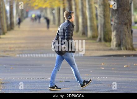 London, England, UK. Young man wearing headphones walking in The Mall, December 2020 during the COVID pandemic Stock Photo