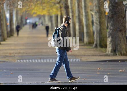 London, England, UK. Young man wearing headphones and a face mask walking in The Mall, December 2020 during the COVID pandemic Stock Photo