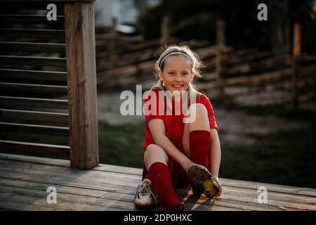 Smiling girl putting football shoes on Stock Photo