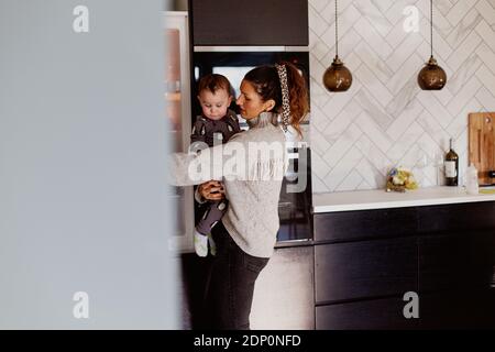 Mother carry toddler son in kitchen Stock Photo