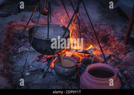 Selective focus on boiling cauldron with mysterious decoction on a campfire at night witch sabbath. Kupala Night, called in Poland Noc Kupaly, Cedynia Stock Photo