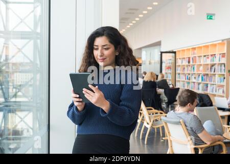 Woman using digital tablet in library Stock Photo