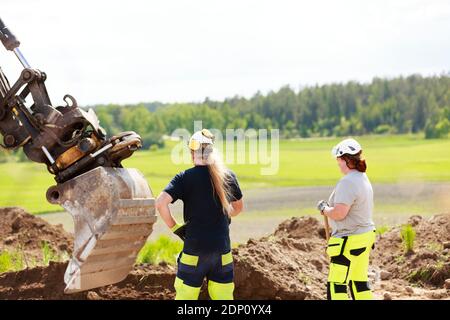 Female workers with digger on background Stock Photo