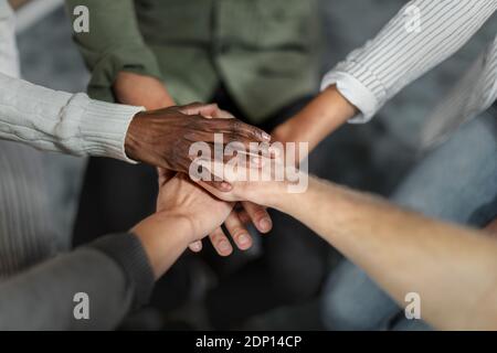 Closeup shot of group of unrecognizable people joining their hands together in huddle Stock Photo