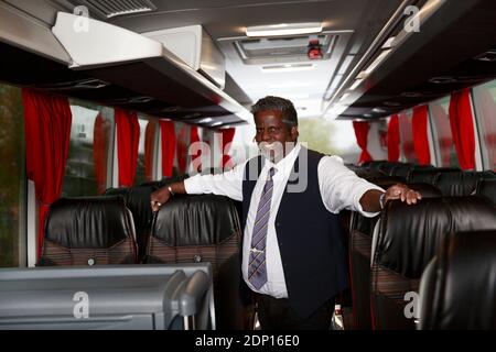 Smiling driver standing in bus Stock Photo