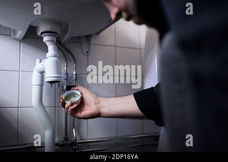 Hands of man fixing drain under bathroom sink Stock Photo