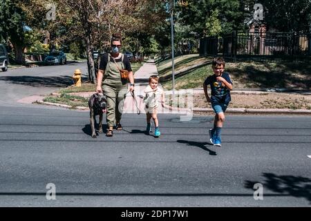 Mother and two boys running across a neighborhood street on sunny day Stock Photo