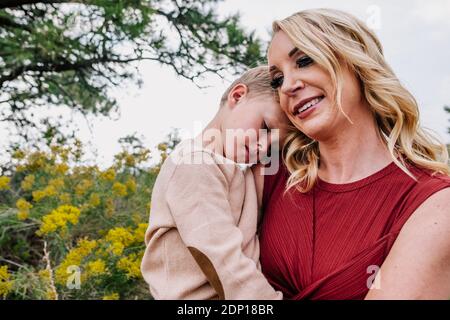 Mother holding and comforting young son outside Stock Photo