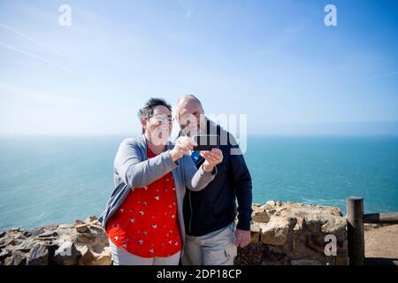 Smiling couple taking selfie, sea on background Stock Photo