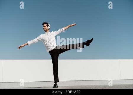 Ballet dancer with headphones practising on roof terrace Stock Photo