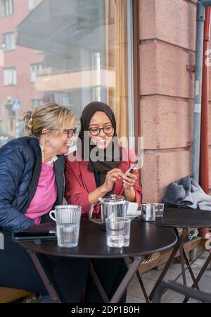 Female friends having coffee in outdoor cafe Stock Photo