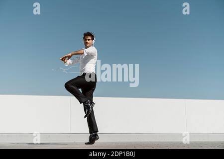 Ballet dancer with headphones practising on roof terrace Stock Photo