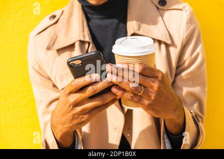 Young man with coffee cup, using smartphone Stock Photo