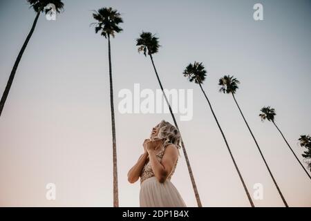 Low angle view of happy bride under palm trees Stock Photo