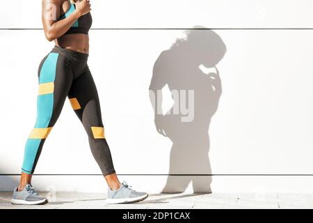 Sportswoman in sports clothing walking against white wall Stock Photo