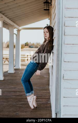 Vertical portrait of teen girl leaning against wall in pointe shoes Stock Photo