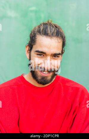Portrait of bearded young man with dyed hair wearing red sweatshirt Stock Photo