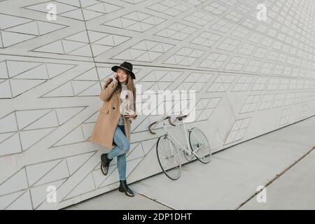 Young hipster woman speaking by phone near to a bicycle Stock Photo