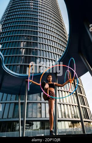 Sporty woman exercising with plastic hoops outside modern office building Stock Photo