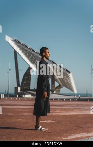 Young man wearing black kaftan under blue sky Stock Photo