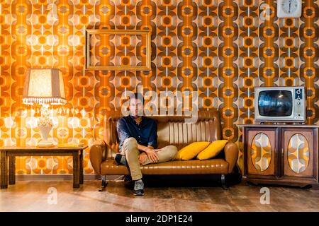 Man sitting on couch in vintage living room Stock Photo