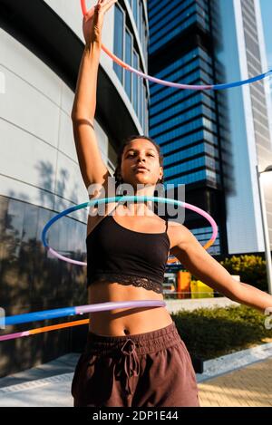 Sporty woman exercising with plastic hoops outside office buildings Stock Photo