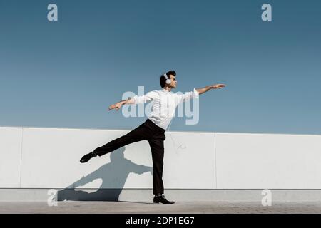Ballet dancer with headphones practising on roof terrace Stock Photo