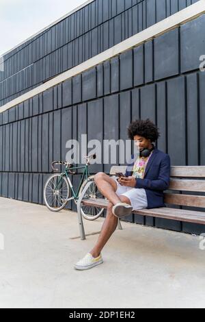 Stylish man using cell phone on a bench Stock Photo